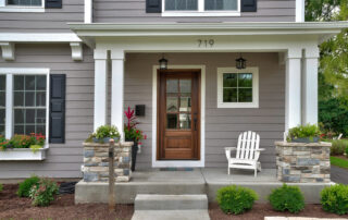 New home with its picture-perfect landscaped yard and inviting windows adorned with shutters and greenery. exterior painting safety