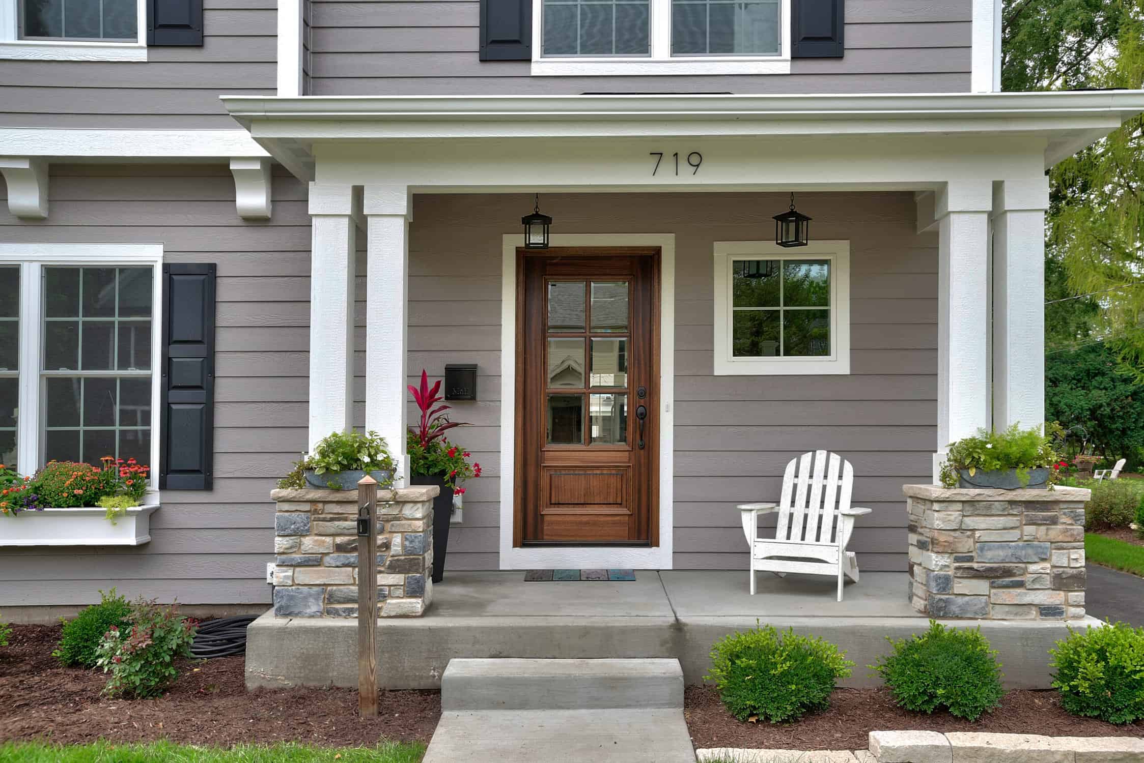 New home with its picture-perfect landscaped yard and inviting windows adorned with shutters and greenery. exterior painting safety