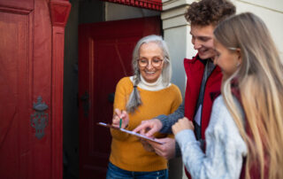 Young volunteers are engaging in door-to-door conversations with an elderly woman, conducting a survey right at her doorstep.