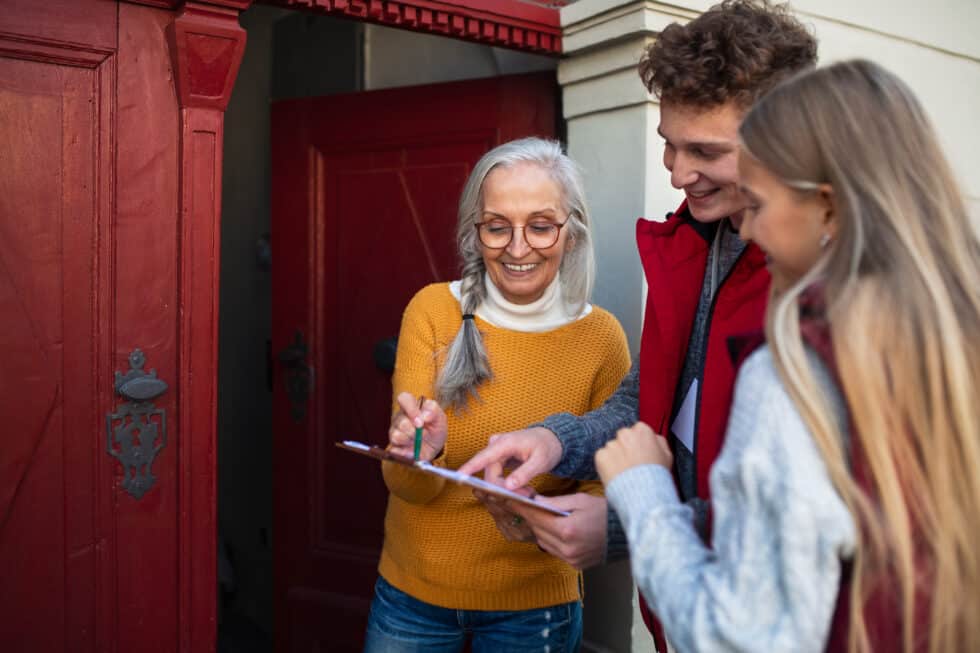 Young volunteers are engaging in door-to-door conversations with an elderly woman, conducting a survey right at her doorstep.