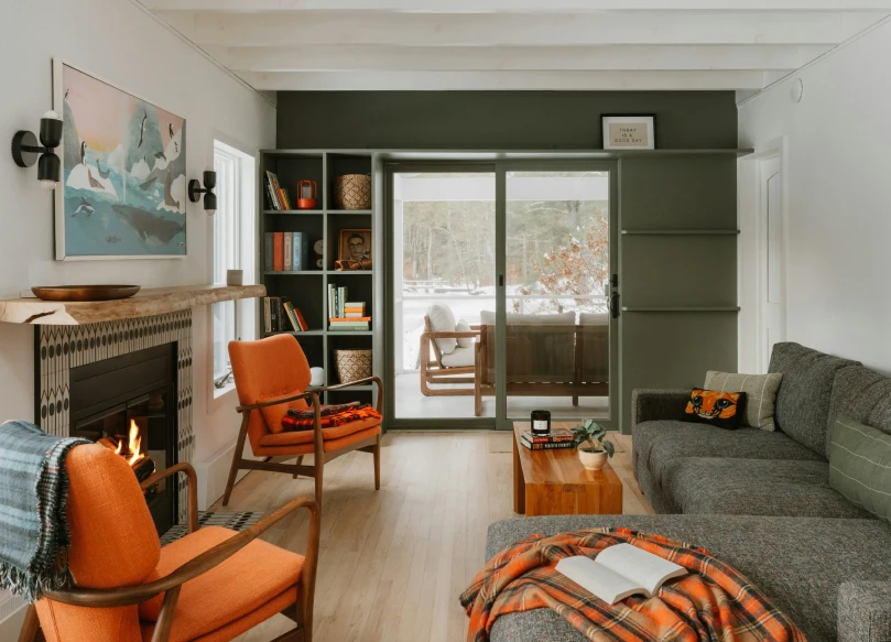 Living room with a dark green accent wall, orange chairs and a fireplace